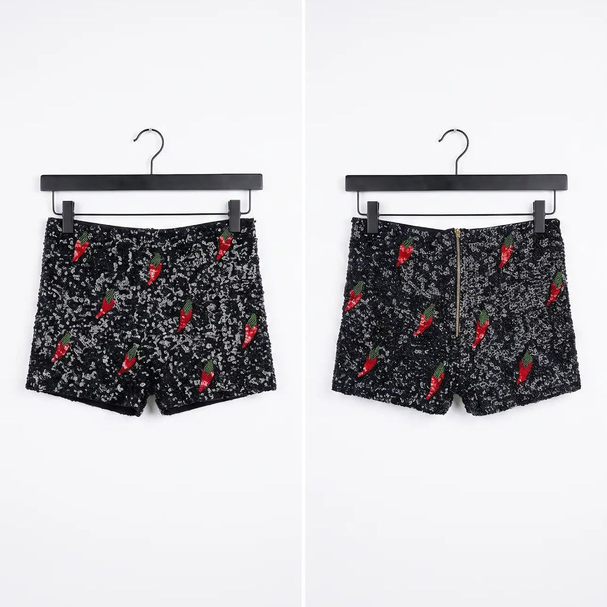 Black shorts with a white speckled pattern and red chili pepper prints, shown from both front and back views on black hangers against a white background.